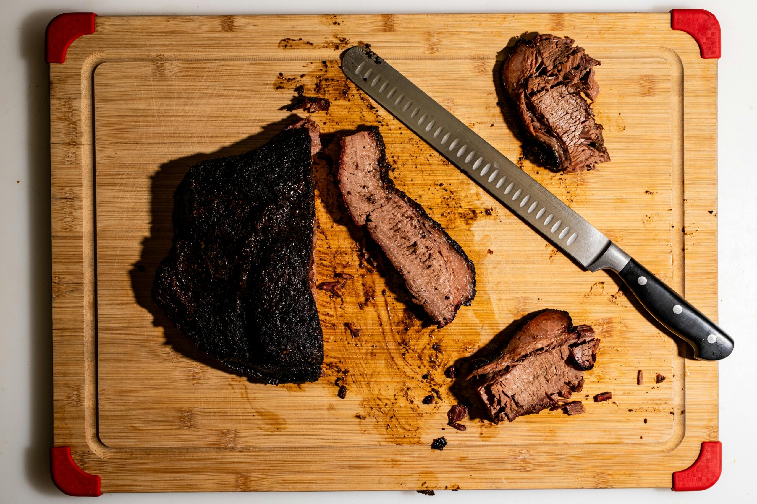 Juicy sliced brisket on a wooden cutting board with a sharp kitchen knife.